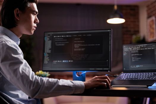 Software developer coding firewall program on monitor and laptop, using encryption server to script security network with binary code. Developing app on data text interface, it programming.