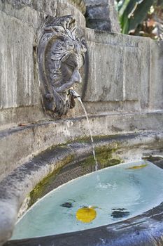 Outdoor fountain with medieval architecture and palm trees at Plaza del Espiritu Santo in Vegueta, Las Palmas de Gran Canaria, Spain