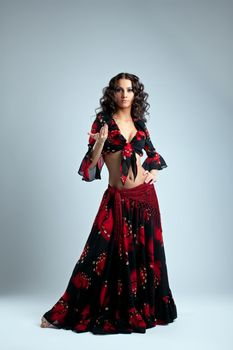 Cute young dancer stand in gypsy costume on grey
