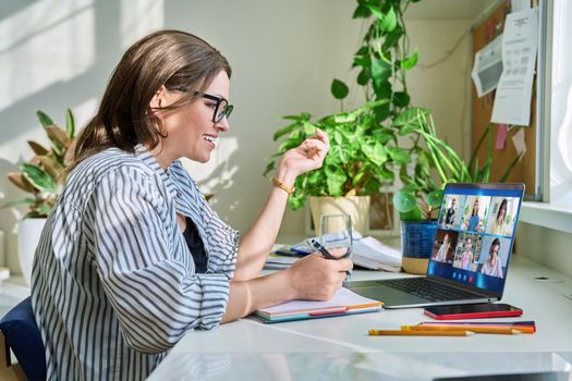 Female teacher working at home remotely, online lesson with group teenage students, teaching looking at laptop screen sitting at home. Distance virtual class course interactive lesson video conference