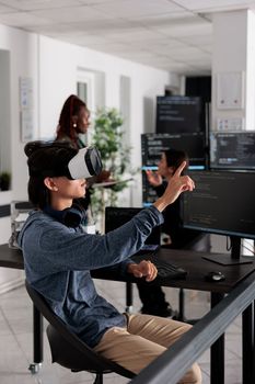 Software developer wearing virtual reality headset working to develop security program in it software company office, Big data admin with vr goggles coding html script with database.