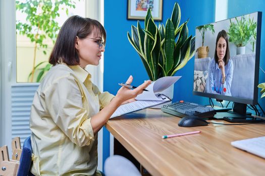 Middle aged woman having video conference call chat with young female on computer screen, in home office. Teacher, business coach, psychologist, therapist looking at webcam, virtual online meeting