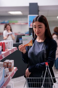 Cheerful pharmaceutical client looking at shelves full of drugs, choosing to buy supplements in drugstore. Pharmacy customer needed healthcare medication to cure disease. Pharmaceutics shop