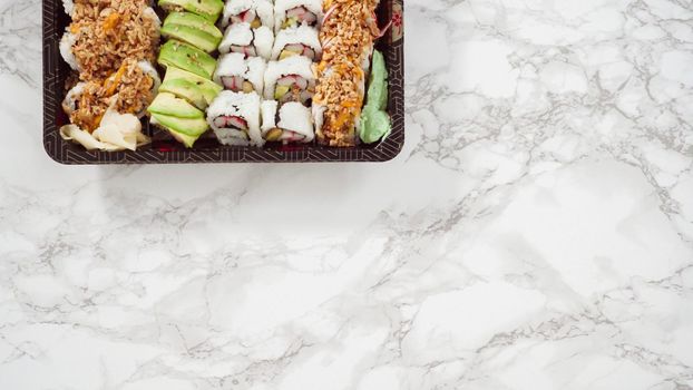 Flat lay. Pre-packaged variety of sushi and sushi rolls in a plastic tray.