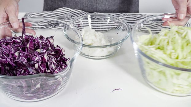 Step by step. Shredded organic cabbage in glass mixing bowls.