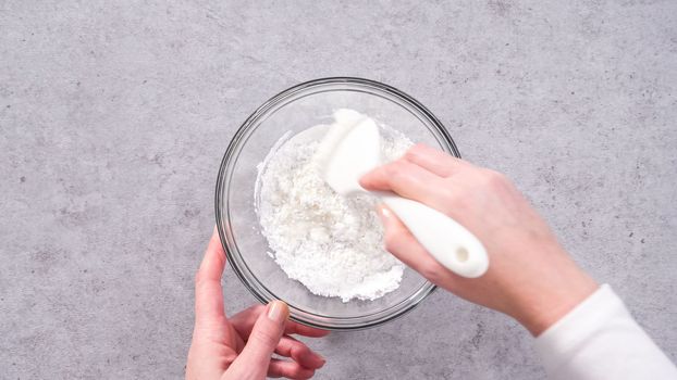 Flat lay. Step by step. Mixing ingredients in a glass mixing bowl to prepare the white glaze.