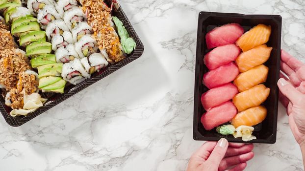 Flat lay. Pre-packaged variety of sushi and sushi rolls in a plastic tray.