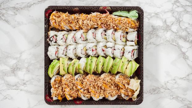 Flat lay. Pre-packaged variety of sushi and sushi rolls in a plastic tray.
