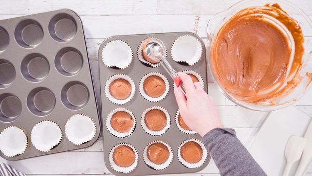 Flat lay. Scooping dough into the foil cupcake liners to bake chocolate raspberry cupcakes.