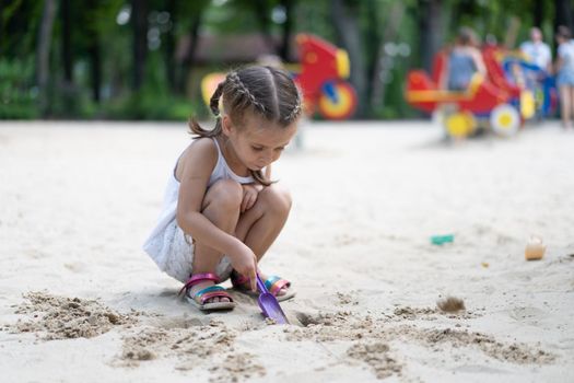 Little Girl Playing Sandbox Playground Digging Sand Shovel Building Sand Figure Summer Day. Caucasian Female Child 5 years Have Fun Outdoor
