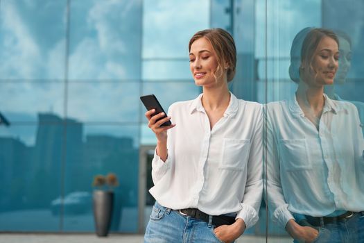 Businesswoman successful woman business person standing outdoor corporate building exterior cell phone Pensive elegance cute caucasian professional business woman middle age dreaming with mobile phone