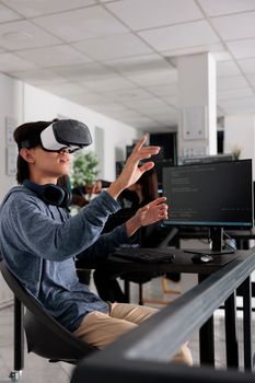 It programmer wearing virtual reality headset to code new server interface, analyzing cloud information on terminal window. Coder programming it database for internet software with vr goggles.