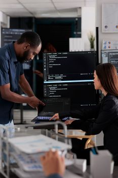 Diverse team of app developers talking about programming in software company office. Artificial intelligence cloud programers compiling code on terminal window server, doing teamwork