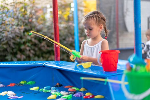 Child Fisher Catching Plastic Toy Fish On Pool Amusement Park Summer Day Little Girl Have Fun On Fishing Carnival Festival Entertainment For Children