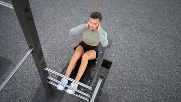 Sit-ups exercises. Active, fit sporty woman doing situps, exercising and training on fitness outdoor gym. One young, serious and athletic female exercising, working out doing physical activity. Banner