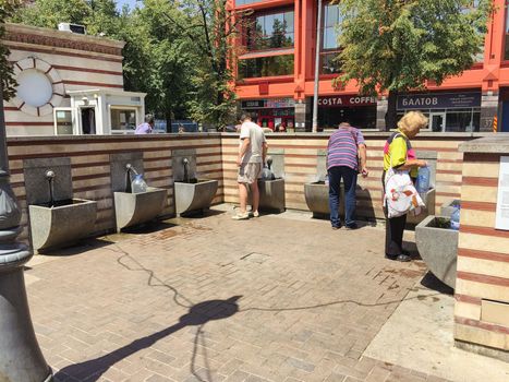 Locals in town to gather water from a public drinking fountain with fresh water. High quality photo