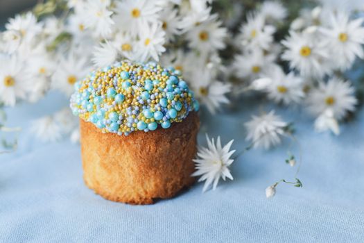 Orthodox Easter cake decorated with beads and daisies in the blue background