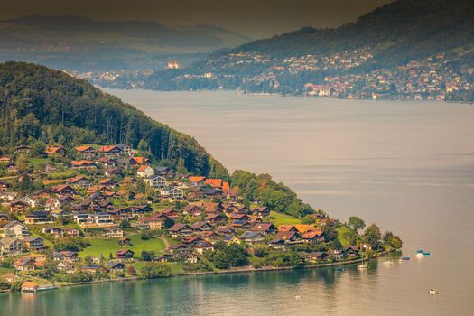 Aerial view of Swiss Alps and Lake Thun with ferry boat at dramatic sunset, Interlaken, Switzerland