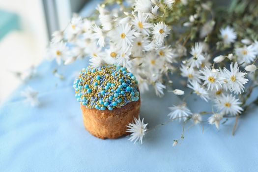 Orthodox Easter cake decorated with beads and daisies in the blue background