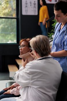 Health specialist helping patient to take off cervical neck collar during rehabilitation therapy and recovery in hospital waiting area. Patient with physical trauma receiving medicine support