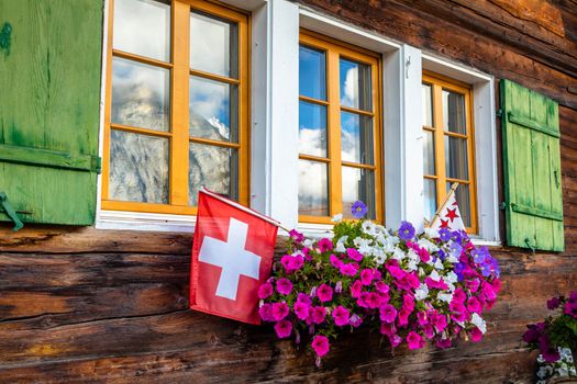 Colorful flowers in rustic balcony at springtime with swiss Flag, Interlaken, Swiss alps