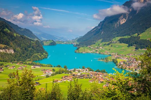 Turquoise Lungernsee and village lungern in the Swiss Alps at sunny day, Switzerland