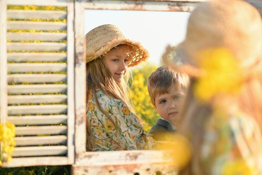 The brother and sister looking in the mirror in the rapeseed field