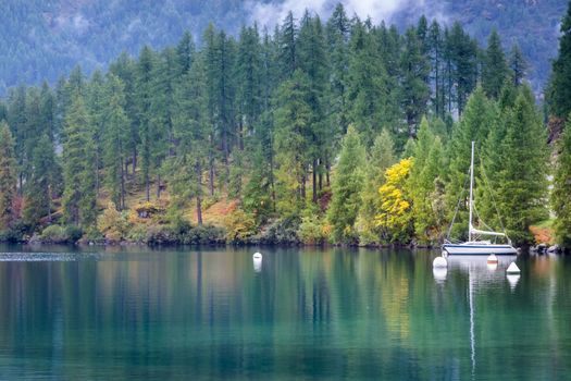 Sailboat anchored on peaceful Silvaplana Lake at misty dawn, Swiss Alps, Switzerland