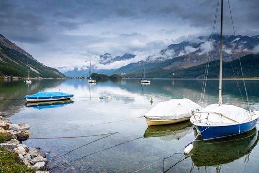 Sailboat anchored on peaceful Silvaplana Lake at misty dawn, Swiss Alps, Switzerland