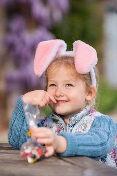 Girl with bunny ears collects chocolate for Easter
