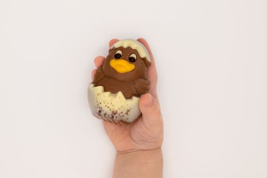 Kid holding figure of isoleted chocolate chicken hatched from an egg for Easter