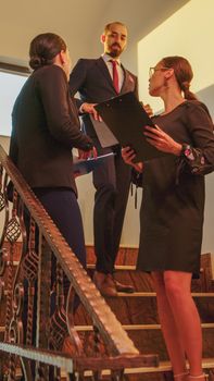 Businesswomen meeting on stairs in finance corporate company analyse graphs standing on stairscase. Group of professional successful businesspeople working in modern financial building