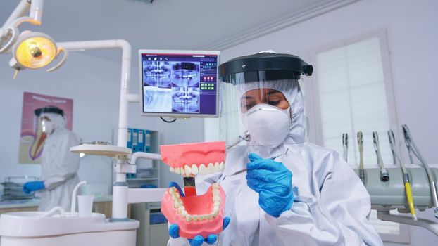 Patient pov of dentist showing correct way of cleaning teeth wearing precaution against covid in dental office using skeleton accessory. Stomatolog wearing safety gear during heatlhcare check