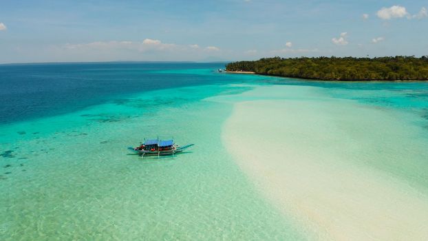 Seascape with a beautiful beach and tropical island surrounded by a coral atoll with turquoise water. Mansalangan sandbar. Summer and travel vacation concept. Balabac, Palawan, Philippines.