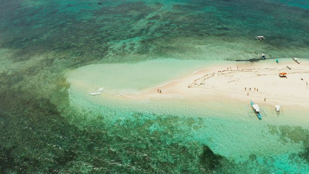 Beautiful beach on tropical island surrounded by coral reef, sandy bar with tourists, top view. Naked Island, Siargao.