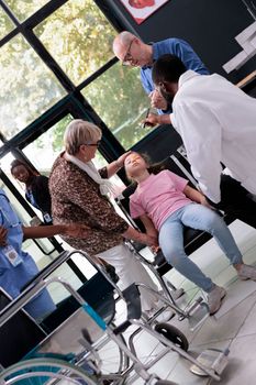 Little girl having chest pain suffering from heart attack in hospital waiting area during medical consultation. Worried grandparents trying to help granddaughter after fainting out. Healthcare service