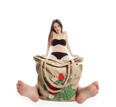 Young woman in black bikini sit with funny beach bag isolated