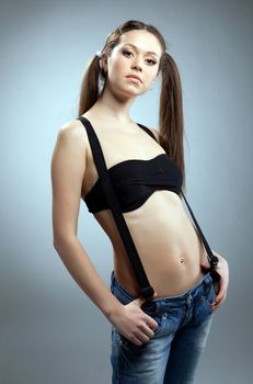 woman in black bikini and jeans with suspenders look at camera