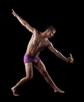 nude athletic man dance striptease with banana in dark