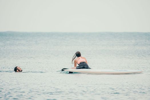 Sea woman and man on sup. Silhouette of happy young woman and man, surfing on SUP board, confident paddling through water surface. Idyllic sunset. Active lifestyle at sea or river