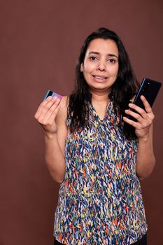 Stressed indian woman buying product in online store, ecommerce website checkout problem, credit card trouble. Irritated person making order, using smartphone, searching goods in internet shop