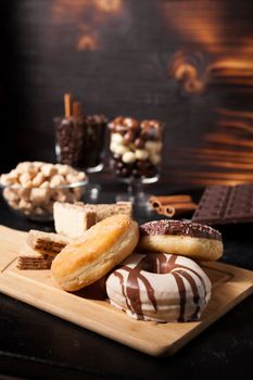 Different type of sweets on wooden board and background