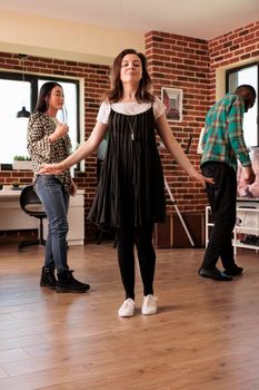 Dancing alone caucasian woman vertical portrait at different ethnicities friends party, gathering. Young adult girl having good time, surrounded by acquaintances, enjoying music, social life.