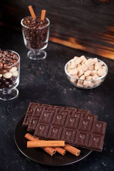 Chocolate tablet next to other candies on dark wooden background
