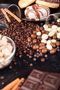 Brown sugar in a glass bowl next to candies and sweets on dark vintage wooden background