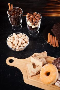 Donuts, peanuts in chocolate and coffee beans on wooden background