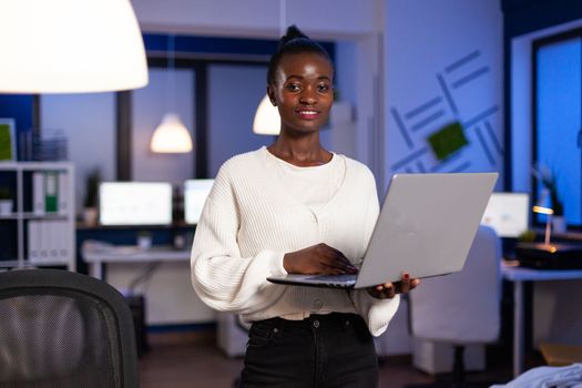Portrait of tired african american businesswoman working at financial strategy late at night in startup company office. Black entrepreneur analyzing management strategy using laptop computer