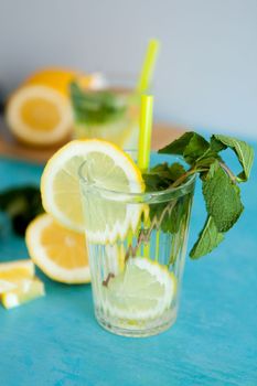 Two glasses with delicious homemade lemonade on gray background sitting on blue desk