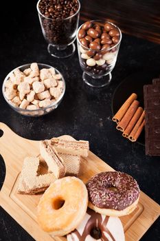 Donuts, peanuts in chocolate and coffee beans on wooden background