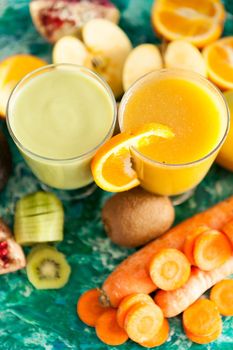 Healthy raw detox smoothies next to fruits and vegetables on wooden background
